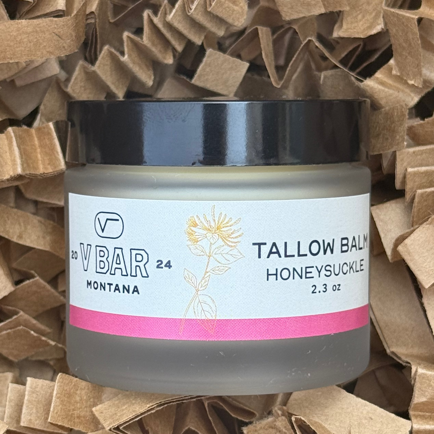 jar of Vbar Montana honeysuckle tallow balm, made from grass fed beef suet on a brown background
