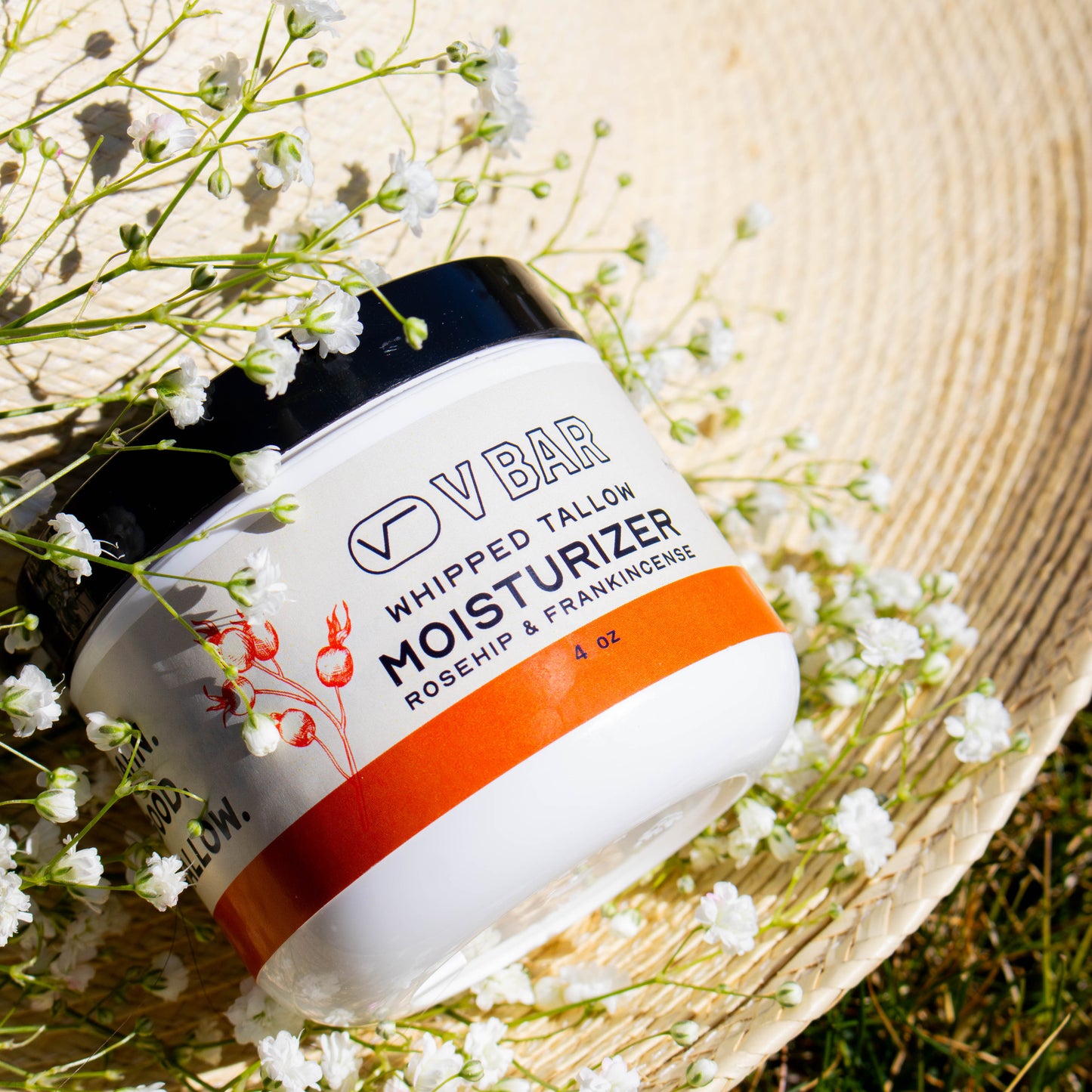 Whipped tallow moisturizer made from grass-fed beef suet sourced from Montana ranches laying in flowers on a straw hat 