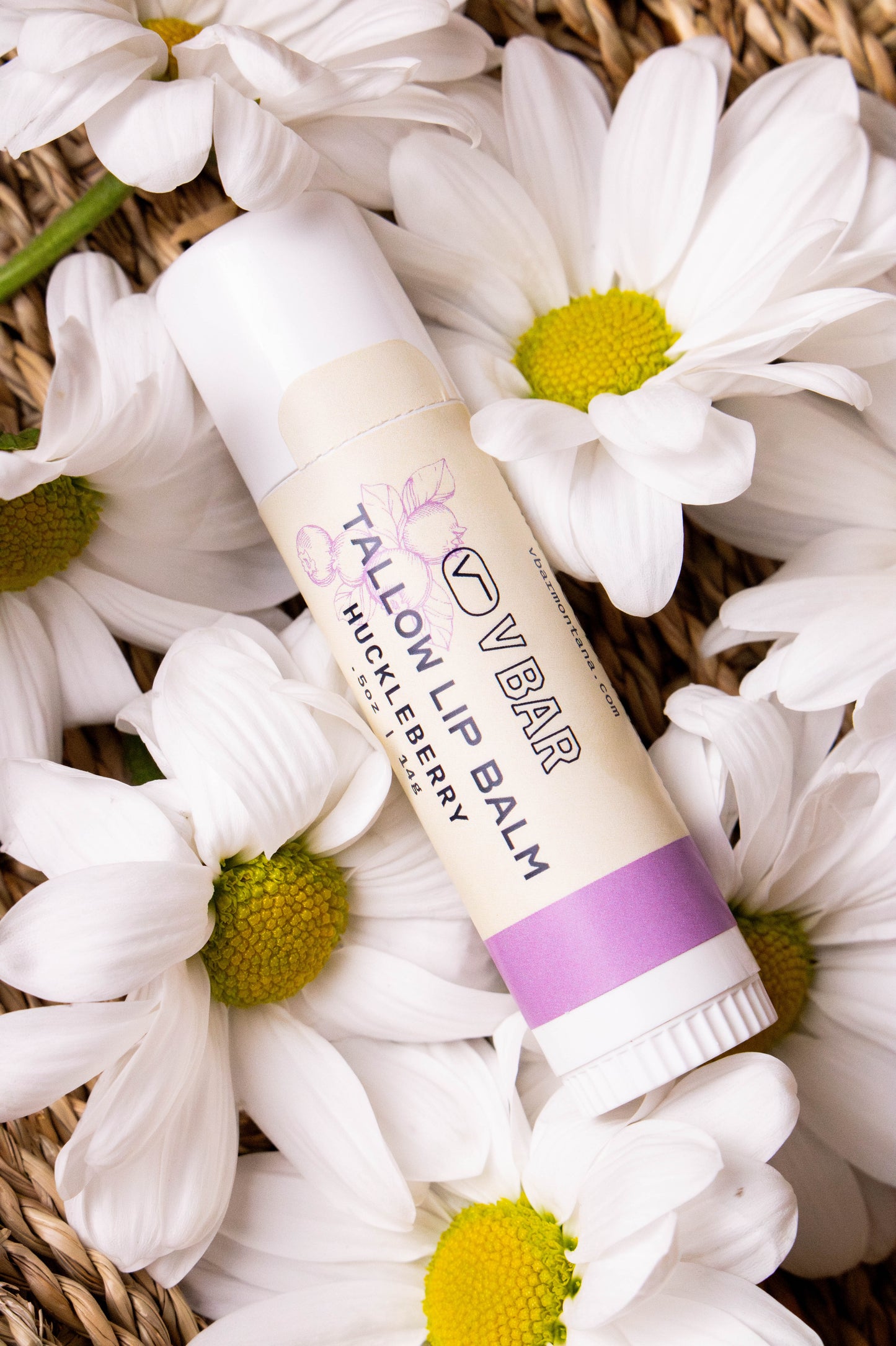 Natural tallow lip balm made from grass-fed beef suet for dry lips and sourced from Montana ranches laying on a bed of flowers