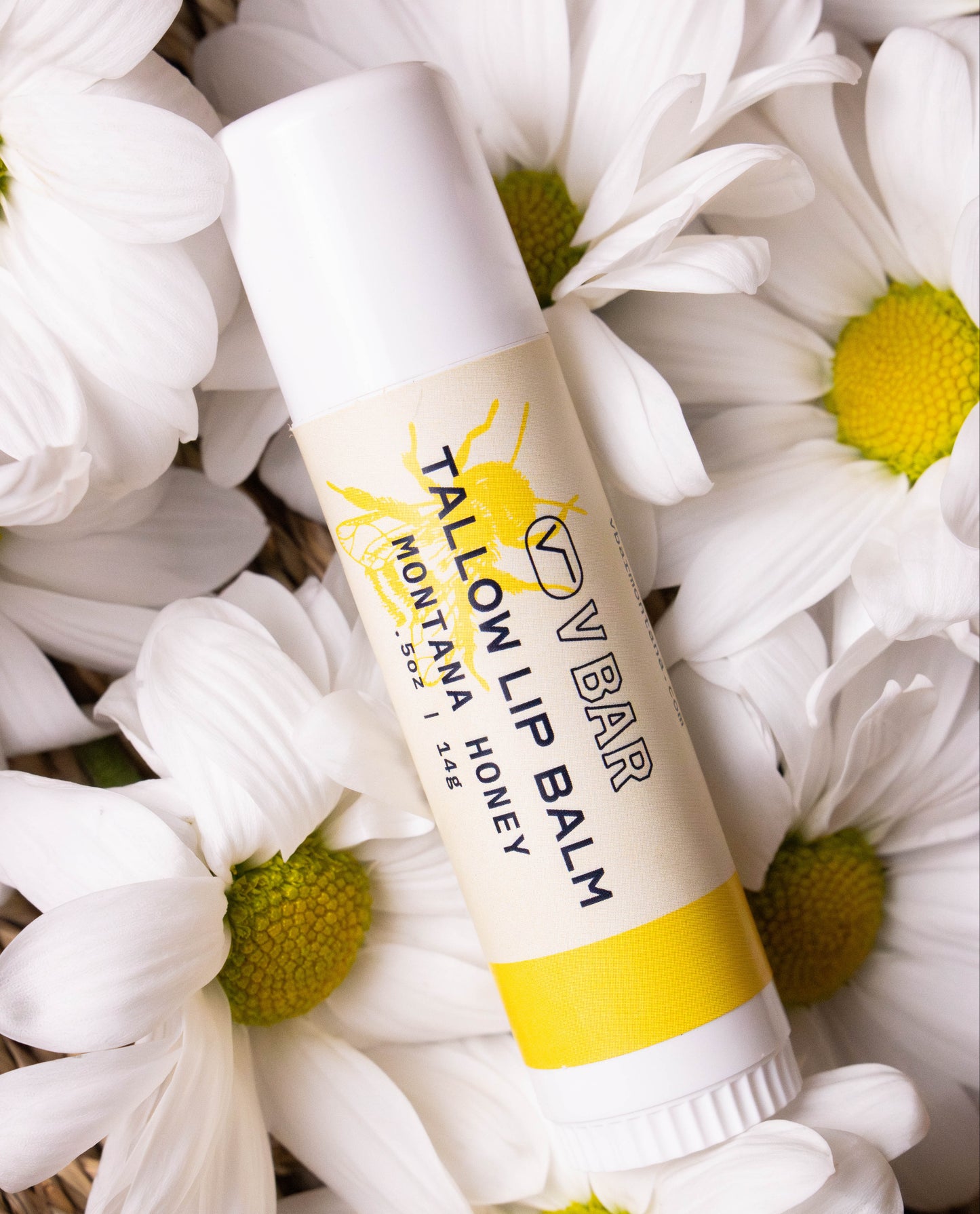 Natural tallow lip balm made from grass-fed beef suet for dry lips and sourced from Montana ranches laying on flowers