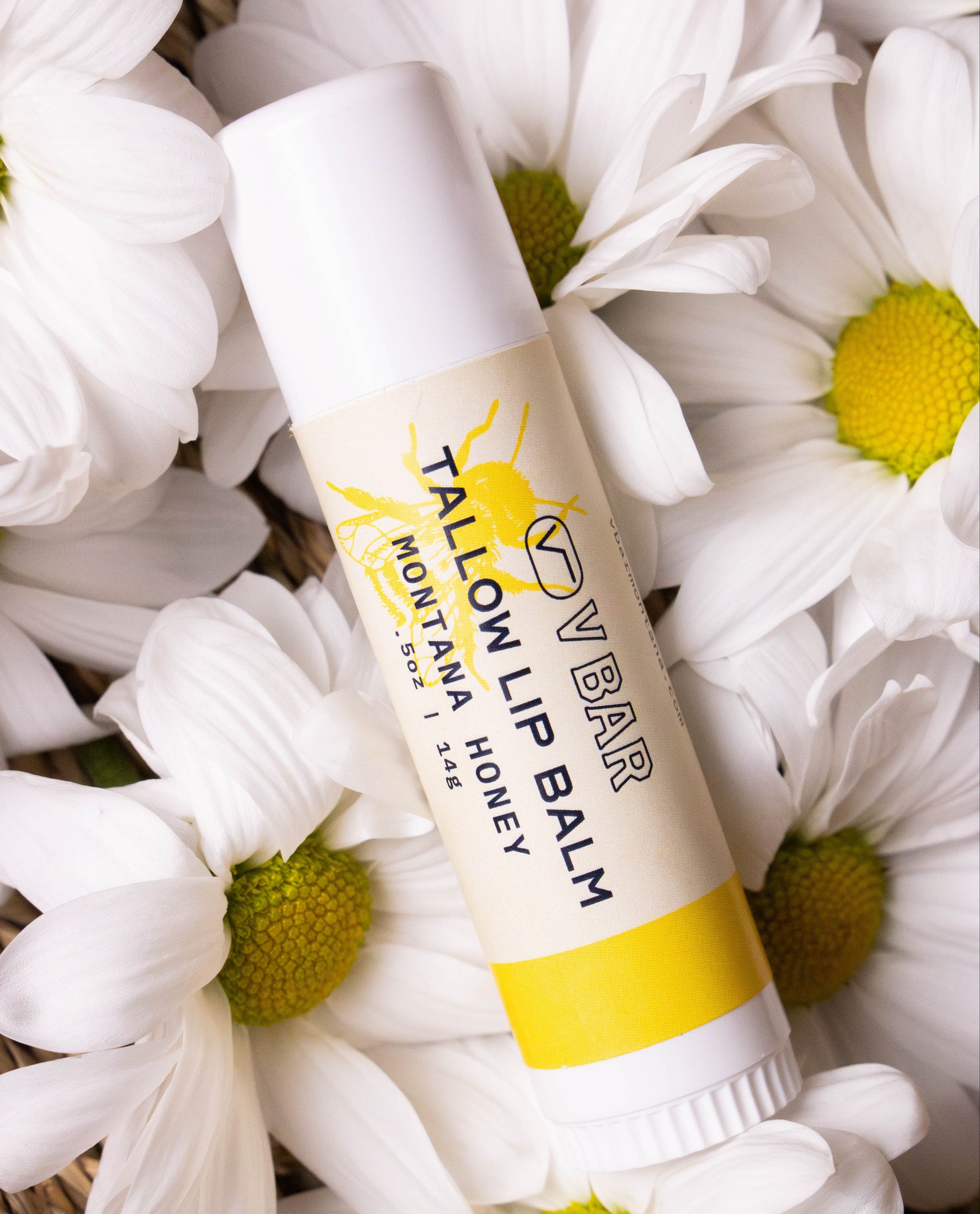 Natural tallow lip balm made from grass-fed beef suet for dry lips and sourced from Montana ranches laying on flowers