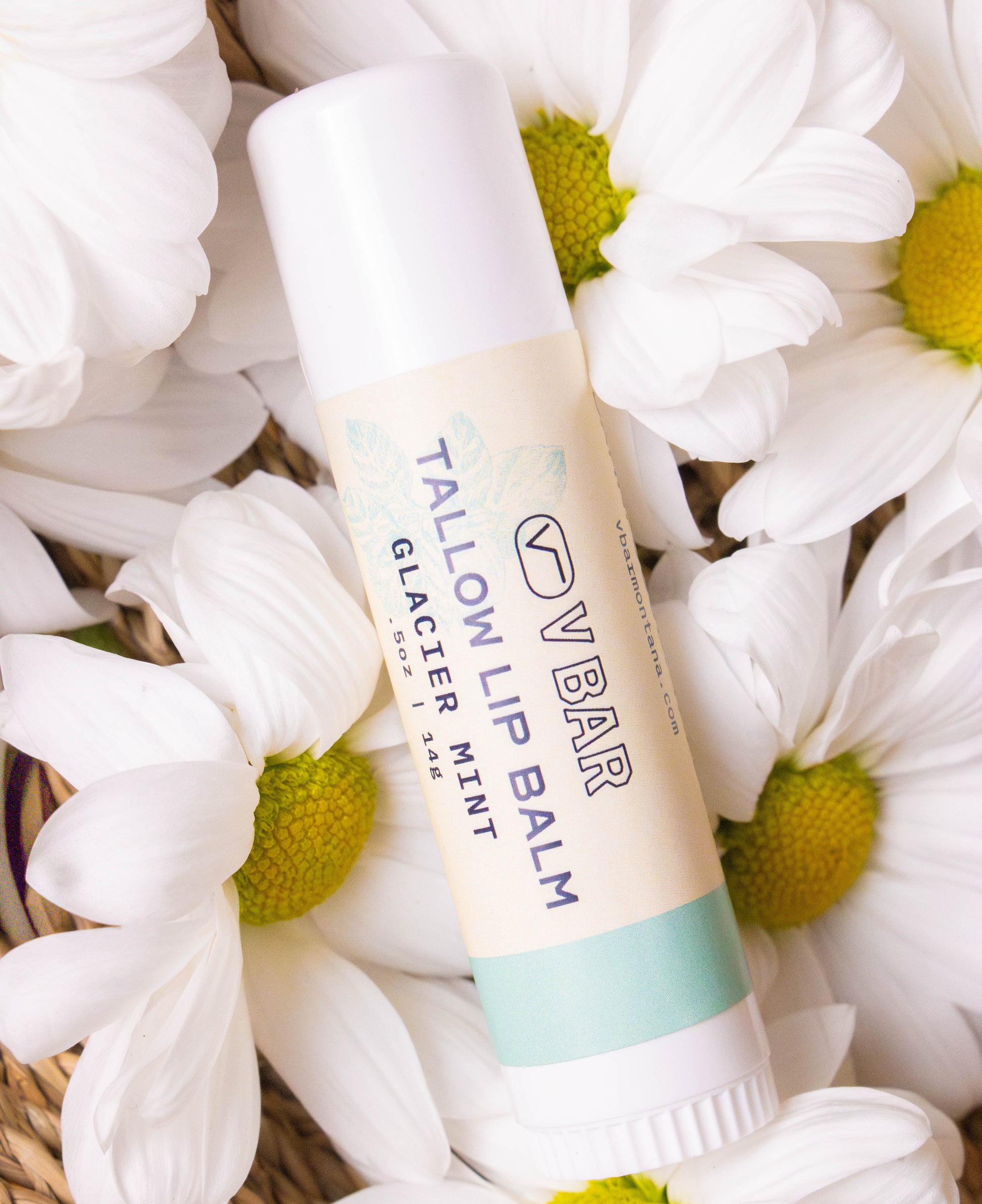 Natural tallow lip balm made from grass-fed beef suet for dry lips and sourced from Montana ranches laying on a bed of flowers